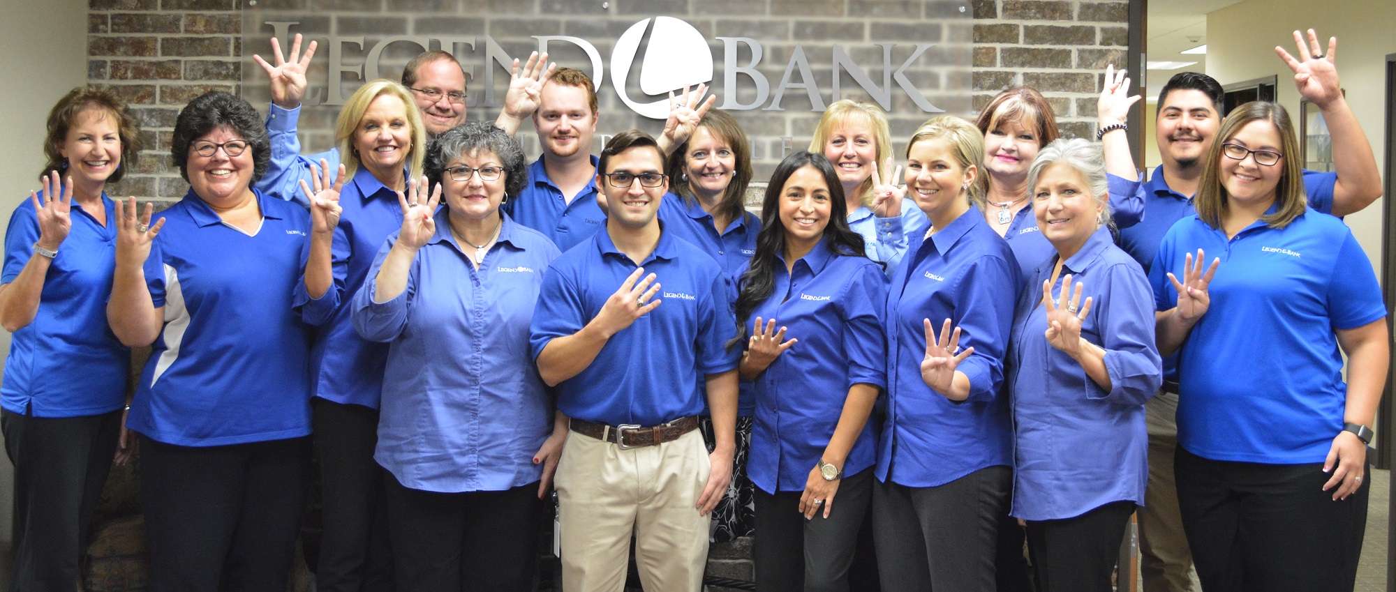 Photo of Legend Bank employees holding up 4 fingers to celebrate Legend Bank being named 4th Best Bank to Work For
